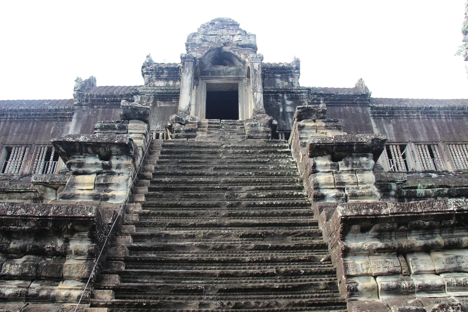 A steep stone staircase leads up to a carved entrance tower at Angkor Wat in Siem Reap.