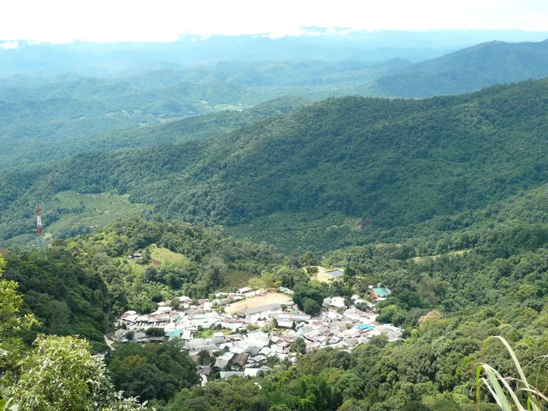 A small hill tribe village nestles in a green valley surrounded by forested mountains near Chiang Mai.