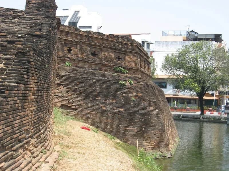 An old brick fortress wall curves along the moat surrounding the old city of Chiang Mai.