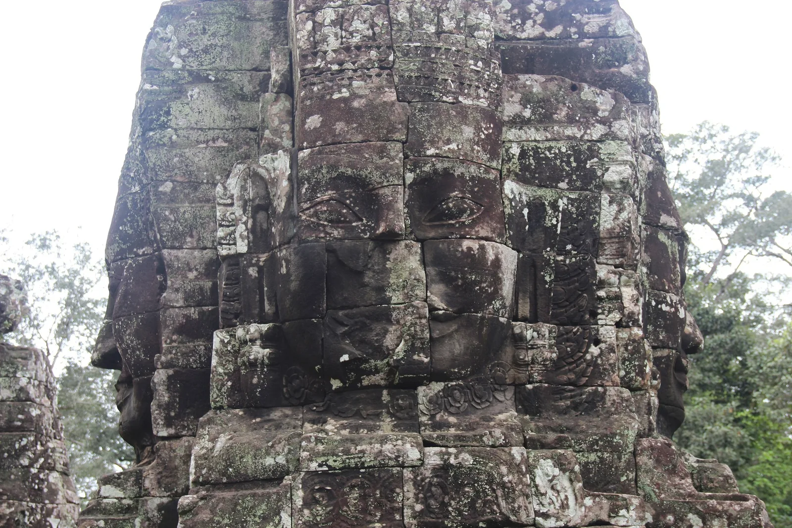 A weathered stone face tower carved into the ancient Bayon temple at Angkor Thom in Siem Reap.